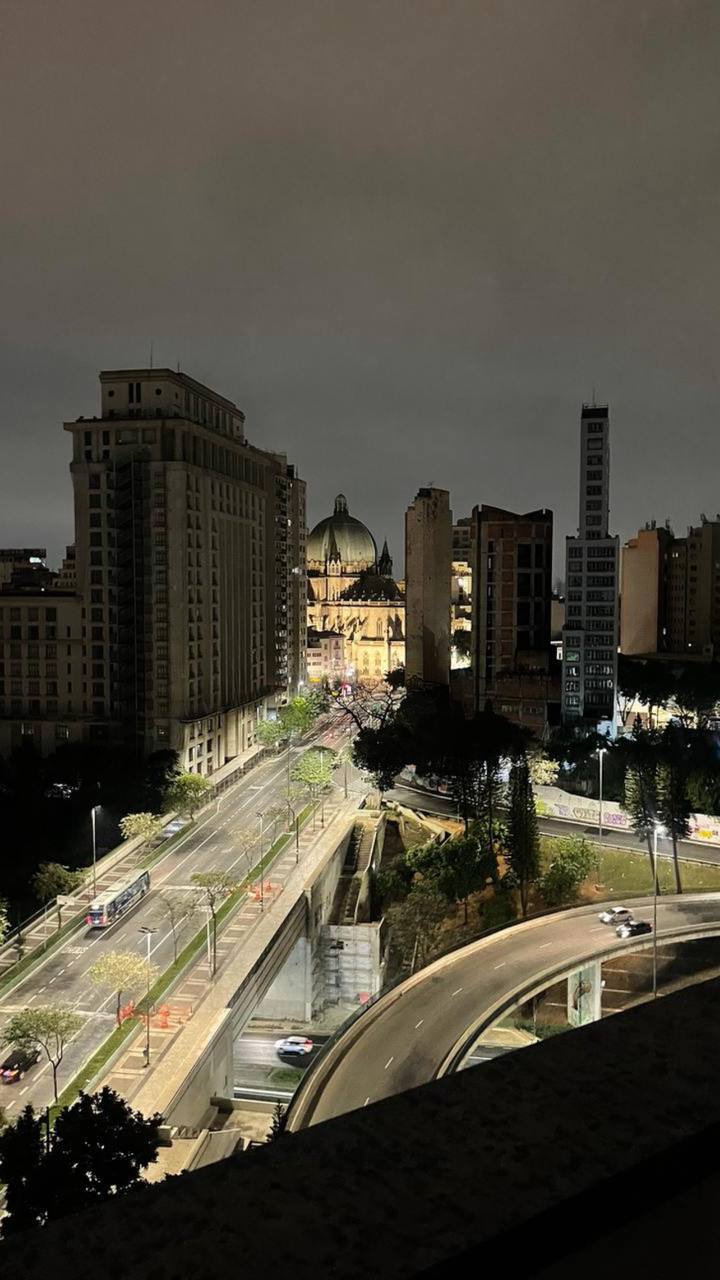 Vista noturna da catedral iluminada entre prédios em São Paulo